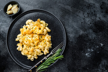 Baked Macaroni Mac and cheese American dish with Cheddar cheese sauce. Black background. Top view....