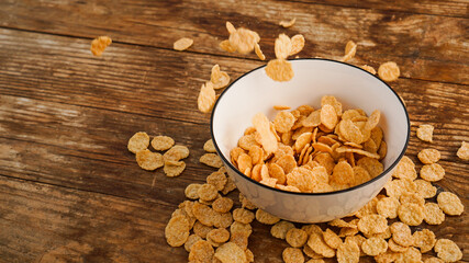 Cereals falling in a white bowl on a wooden table