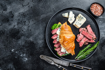 Croissant Sandwich with Fillet Mignon tenderloin meat steak with blue cheese. Black background. Top view. Copy space