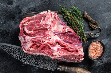 Raw Boneless Leg of Lamb meat on wooden cutting board. Black background. Top view