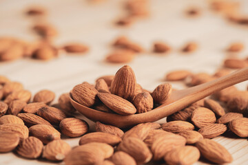 Almonds nut in wooden spoon and pour on table with copy space. Almonds nut is healthy diet food which high protein low fat and essential amino acid.