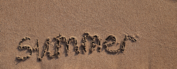 The word summer written on sand