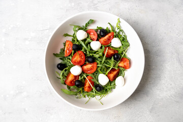 Mediterranean diets food. Mozzarella salad with tomatoes black olives arugula and olive oil. dish of Italian Greek cuisine. Healthy eating