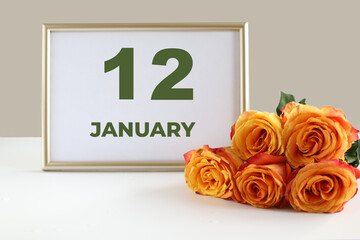 day of the month 12 January calendre photo frame and yellow rose on a white table