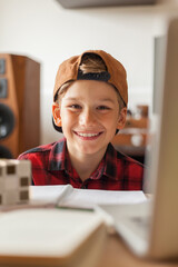 Happy elementary student with a cap at home.