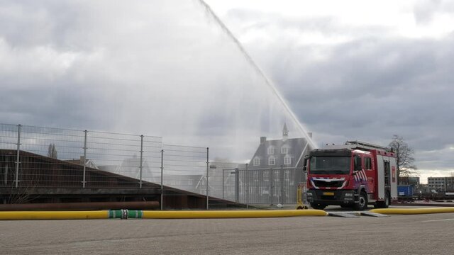 Fire brigade firetruck exercise water jet hoses in Dutch harbor Huizen