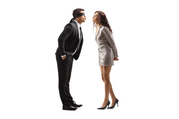 Full length profile shot of a man in a suit with blindfold kissing a woman in a dress