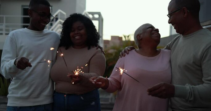 Happy african family celebrate outdoor with firework sparklers - Family, love and lifestyle concept