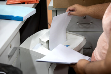 Secretary destroys documents using a shredder. 