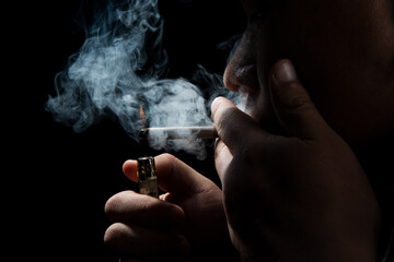 Close up young man smoking a cigarette black background