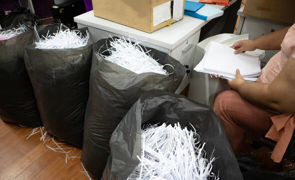 Secretary destroys documents using a shredder. 