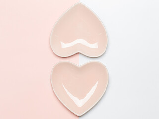 Two pink heart shaped plates on pink and white background