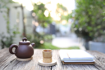 Bamboo cup and tea pot with notebooks on wooden table