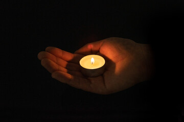 Candle in hands on black background
