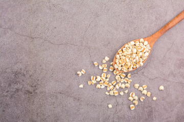 Vegan and healthy food concept. Job's tears with a wooden spoon on the black table. Top view.