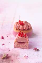 Pink Chocolate Ruby and Red Currant Oval Mini Cakes, on the light pink background with dried rose buds.