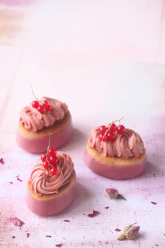 Pink Chocolate Ruby and Red Currant Oval Mini Cakes, on the light pink background with dried rose buds.