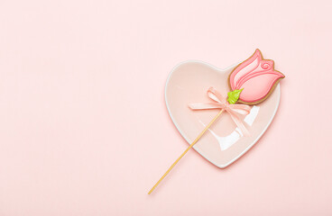 Cookies on a stick tulip on a pink plate in the shape of a heart on a pink background