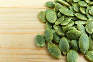 Unsalted Green pumpkin seed on wooden board.