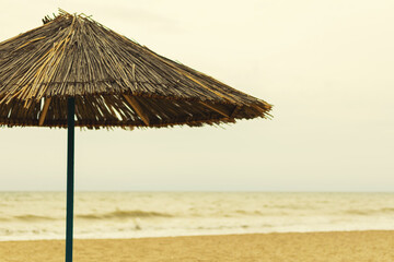 Beach umbrella made of straw by the sea.