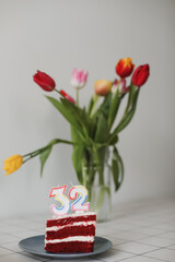 Birthday cake with 32 number candle and a bouquet of flowers