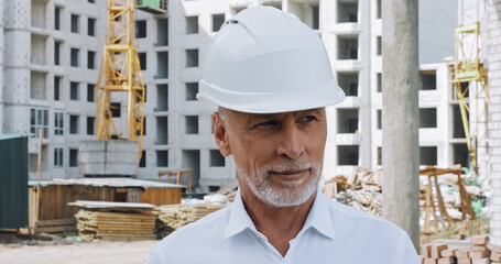 Smiling engineer looking away near building on background