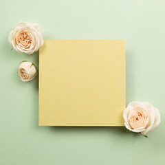 Yellow memo pad with rose flowers on green background. top view, copy space