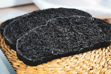 Pieces of black fresh bread with the addition of activated carbon on the table.