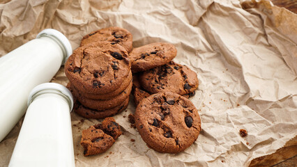 Cookies with chocolate drops on craft paper and bottles of milk