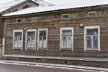 An old one story wooden house with a roof covered with snow