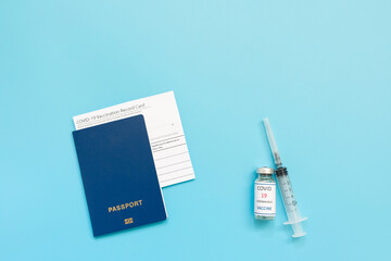 Vaccination card, passport, a vial with covid-19 vaccine. syringe and mask on a blue background, close up, copy space. Immunity passport, risk-free concept.