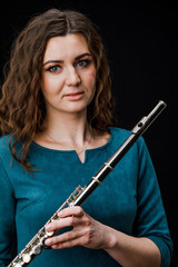 Portrait of a woman playing a transverse flute, isolated on a black background.