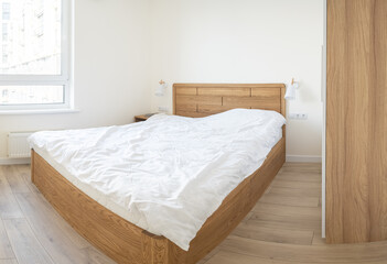 Fototapeta na wymiar Wooden bed with white linens.