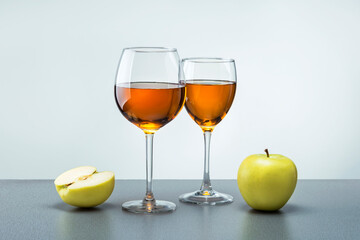 Two glasses of apple juice with fruit apples on grey surface. Healthy food concept.