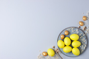 Grey plate with easter yellow eggs and flowers on grey background. Flat lay, copy space.