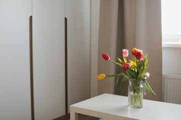  tulips on a table in a glass vase on a sunny day