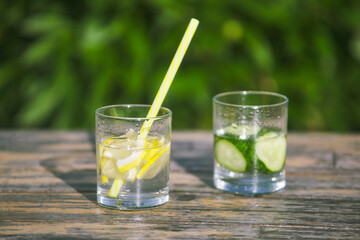 fresh lemon and cucumber lemonade. drinking straw in glass. chopped fruit slices in water