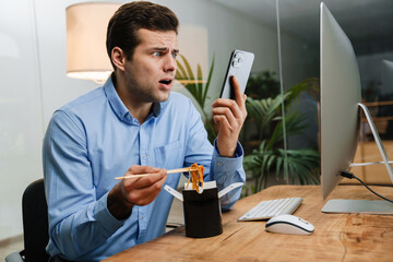 Confused handsome young business man using mobile phone