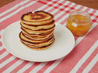 Close-up of delicious pancakes, with fresh blueberries, strawberries and maple syrup on a light background. With space to copy. Sweet maple syrup flows from a stack of pancakes