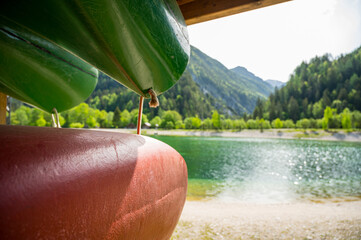 Colorful canoes stacked at lakeshore ready to be rented.