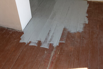 Malowanie starej podłogi z desek na kolor jasnoszary.
