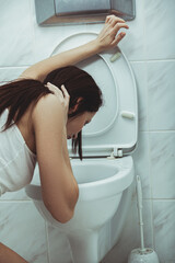 Woman vomits in to the toilet in the bathroom. Young woman vomiting into the toilet bowl in the...