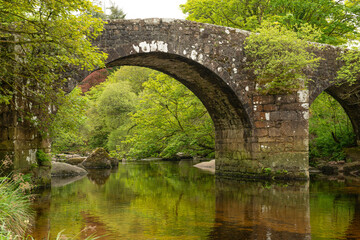 Medieval old stone bridge over an idyllic small river in a green landscape