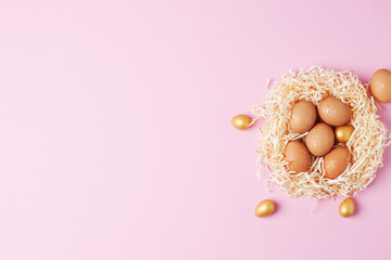 Nest with easter eggs with flowers on pink background. Flat lay, copy space