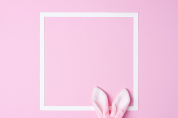 Bunny ears with white frame on pink background. Flat lay, copy space