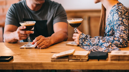 couple holding glass with espresso martini cocktail, decorated with coffee bean. Smooth image with shallow depth of field.