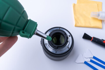 Photographer blows bullets from the camera lens. Camera cleaning accessories on white background
