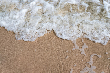 Close-up of wave on sandy beach with copy space for your text, top view background.