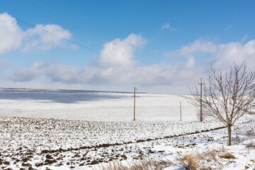 Snow-covered agricultural fields. Black earth under the snow	