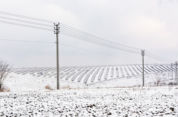 Electric cables on a winter field. Solar panels on the field.